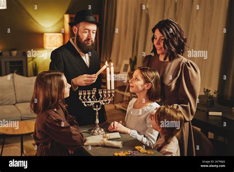 Portrait of orthodox jewish family lighting menorah candle together ...