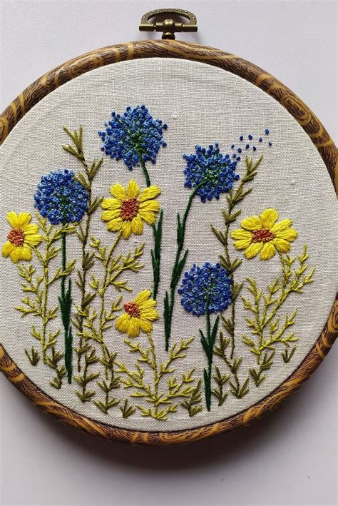 A Close Up Of A Embroidery On A Wooden Hoop With Flowers In It And Blue