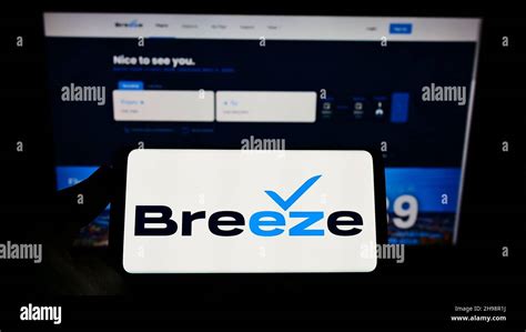 Person Holding Smartphone With Logo Of US Airline Company Breeze