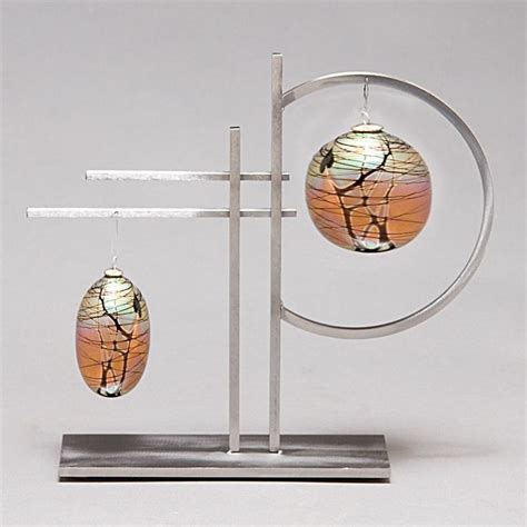 A Pair Of Earrings Is Displayed On A Metal Stand With Two Glass Drops