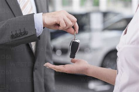 At The Car Dealer Salesman Handing Over Car Key To Client Stock Photo