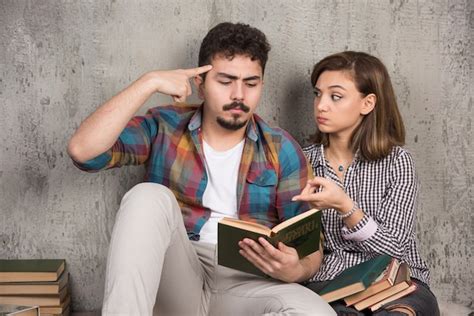 Jeune Couple Souriant Assis Sur Le Sol Avec Des Livres Photo Gratuite