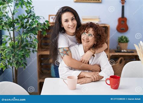 Two Women Mother And Daughter Drinking Coffee Hugging Each Other At