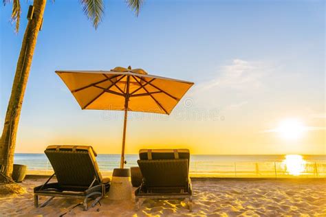 Beautiful Tropical Nature Umbrella Chair With Palm Tree Around Beach Sea Ocean At Sunset Or