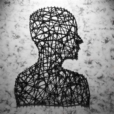 Perfil de escultura de arame preto e branco cercada por mármore, uma