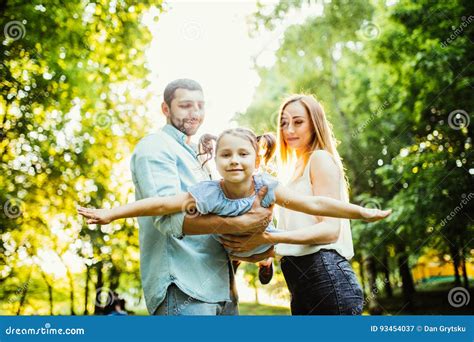 Den Lyckliga Unga Familjen Med Ett Barn Som Har Gyckel I Sommarstad