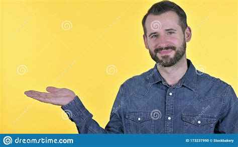 The Portrait Of Young Man Holding Product On Hand Yellow Background