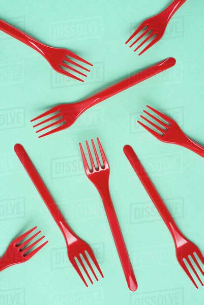 Top View Of Red Plastic Forks Scattered On Blue Background Stock