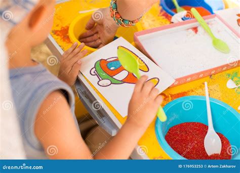 A Child Draws With Colored Sand Picture Cartoon Characters Stock