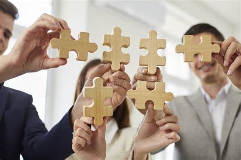 Group Of Business People Assembling Jigsaw Puzzle At Office