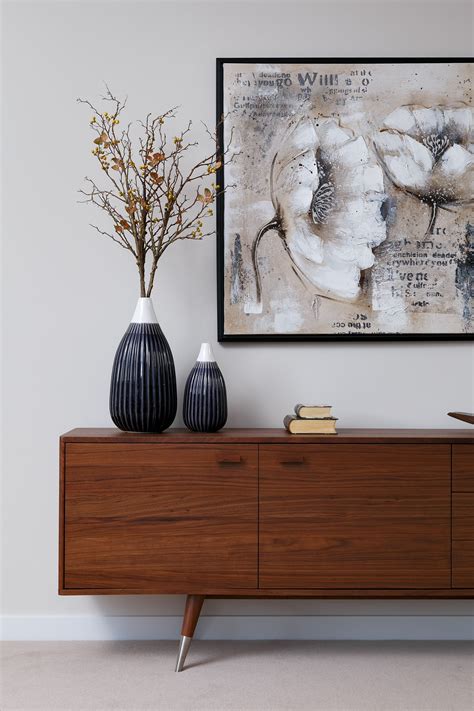 Two Vases Sitting On Top Of A Wooden Dresser Next To A Framed Art Piece