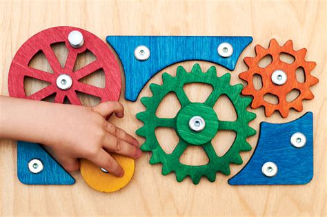 Childrens Hand Rotates And Adjusts Toy Wooden Gears Of A Complex