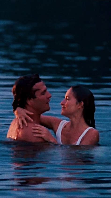 A Man And Woman In The Water Embracing Each Other With Their Arms