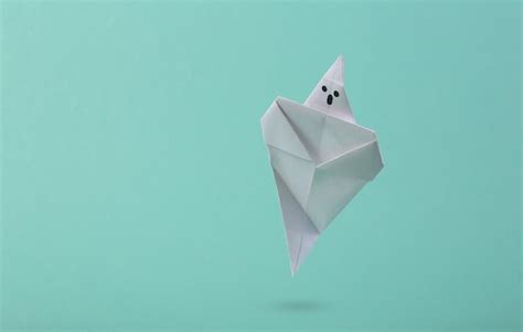 Premium Photo | Soaring origami ghost on a blue background creative ...