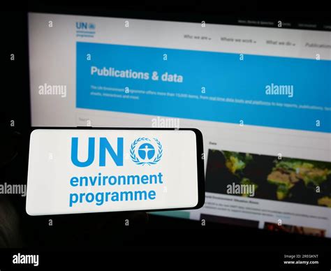 Person Holding Mobile Phone With Logo Of United Nations Environment Programme Unep On Screen