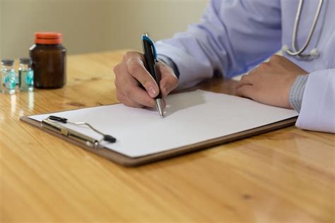 Premium Photo Midsection Of Doctor Writing Prescription On Table