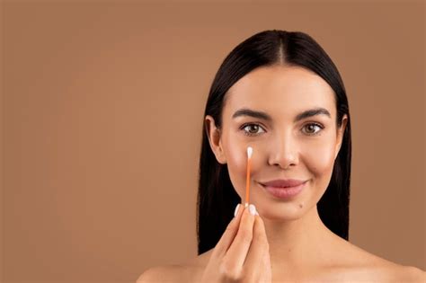 La mujer quita el maquillaje de la cara con un hisopo de algodón Foto