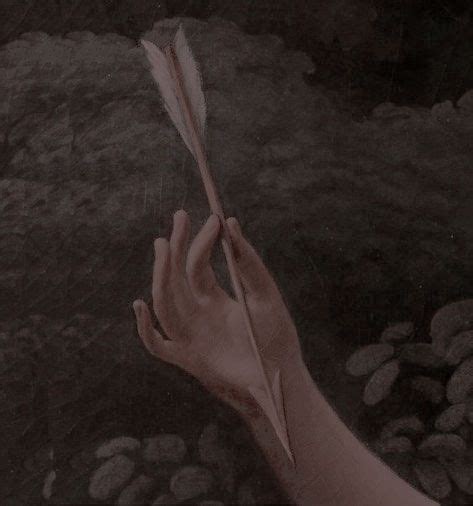 A Person S Hand Holding A Feather On Top Of Rocks