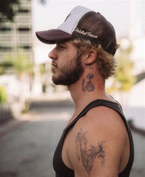 A Man With A Tattoo On His Neck And Shoulder Standing In The Street