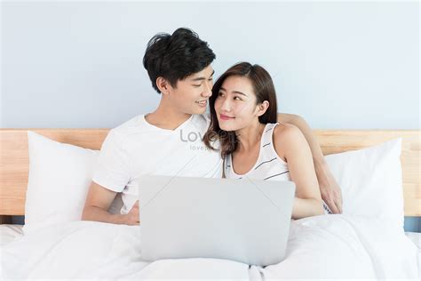 침대에 누워 컴퓨터를 보고 있는 젊은 커플 사진 무료 다운로드 Lovepik