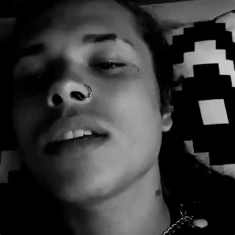 A Man Laying On Top Of A Bed With His Nose Piercing In Black And White