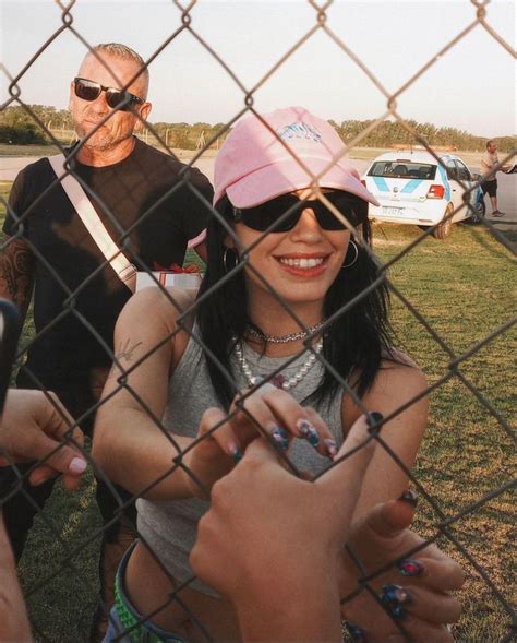 Two People Standing Behind A Chain Link Fence