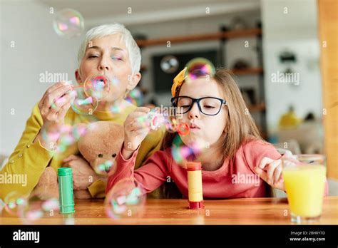 Portrait Of Grandmother And Granddaughter Having Fun Blowing Soap