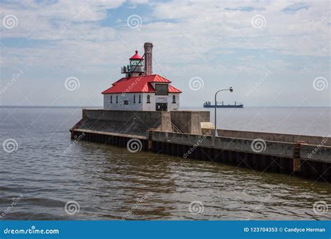 Red Roof Lighthouse With Cargo Ship Passing Editorial Stock Photo