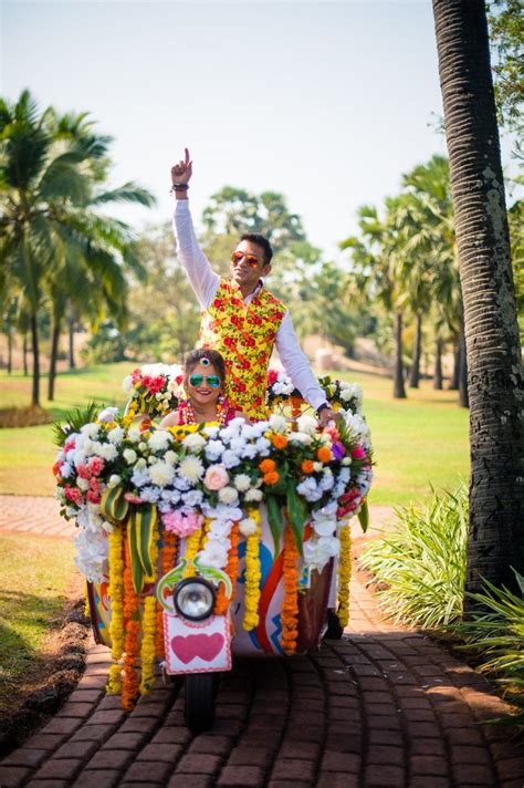 A Man And Woman Riding On The Back Of A Colorful Cart In Front Of Palm