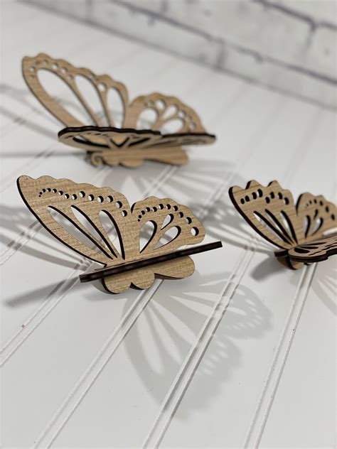 Three Wooden Butterflies Sitting On Top Of A White Table