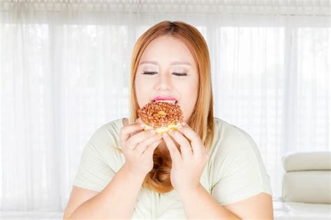 Premium Photo Overweight Woman Eating Donuts At Home