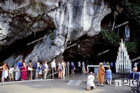 Pilgrims Visiting The Our Lady Of Lourdes Statue In The Cave At