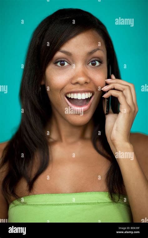 Portrait Of African Woman Talking On Mobile Phone With Surprised Smile