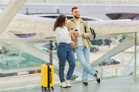 Man And Woman With Takeaway Coffee Waiting Flight At Airport Stock