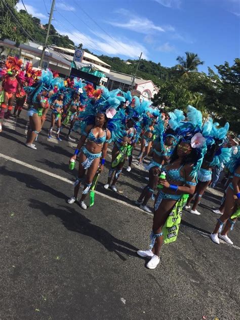 a group of women in blue and green costumes marching down the street at a carnival