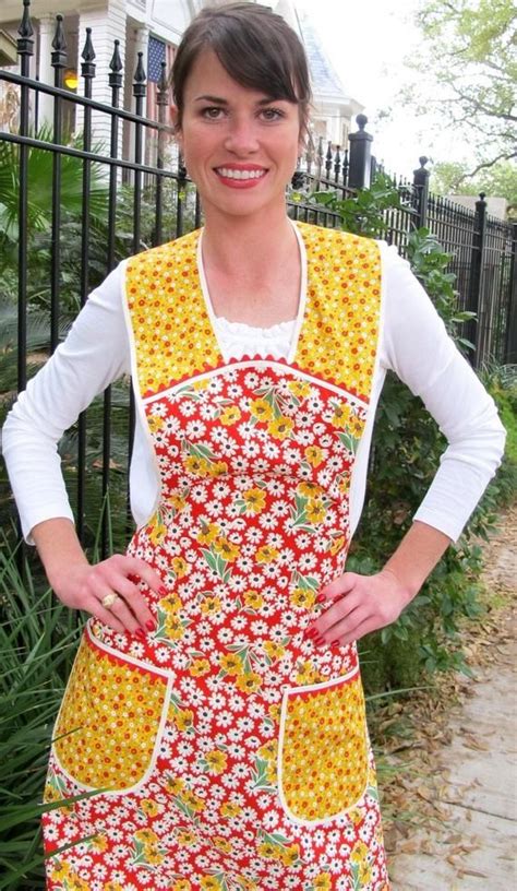 A Woman Standing In Front Of A Fence Wearing An Apron And Smiling At