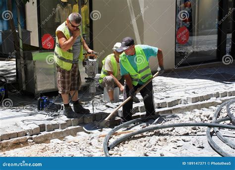 Construction Workers Digging And Paving Tiles On A Street In The Center