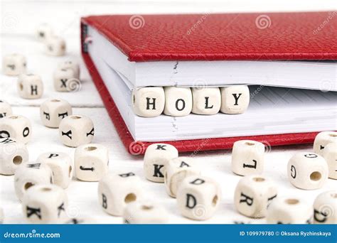 Word Holy Written In Wooden Blocks In Notebook On White Wooden T Stock