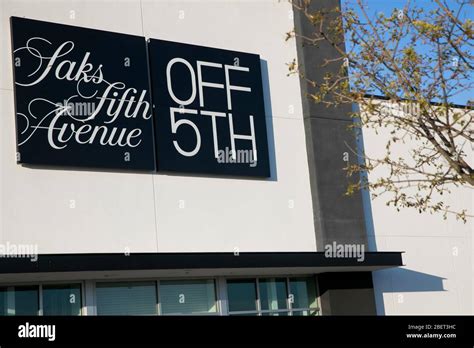 A logo sign outside of a Saks Fifth Avenue OFF 5TH (Saks Off Fifth ...