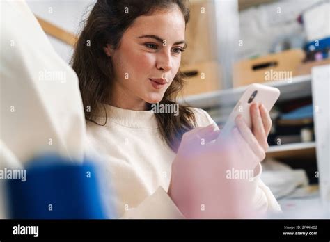 Joyful Nice Brunette Girl Seamstress Using Mobile Phone While Working In Atelier Stock Photo Alamy