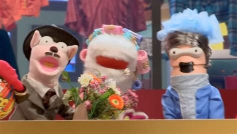 Three Puppets Are Sitting On A Table With Flowers In Front Of Them And