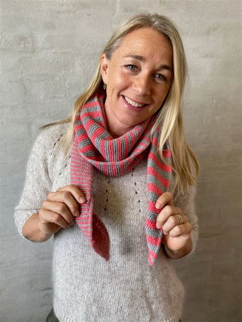 A Woman Wearing A Pink And Grey Scarf With Red Stripes On It Smiling