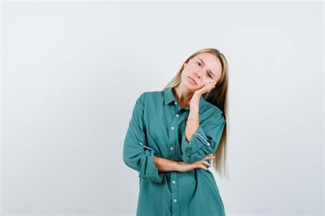 Fille Blonde Se Penchant Joue Sur La Paume Tenant La Main Sur Le Coude En Blouse Verte Et La