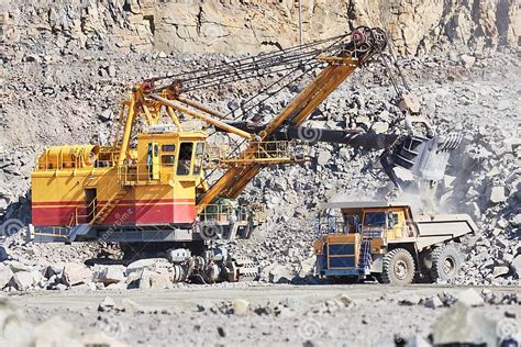 Excavator Loading Granite Or Ore Into Dump Truck At Opencast Stock