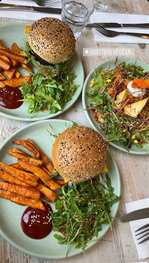 Three Plates With Burgers Fries And Salad On Them Sitting On A Wooden