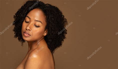 Señora afroamericana joven desnuda posando sobre fondo de estudio