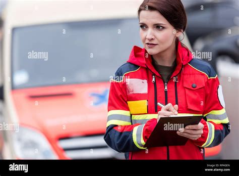 Female paramedic in red uniform writing in clipboard Stock Photo - Alamy