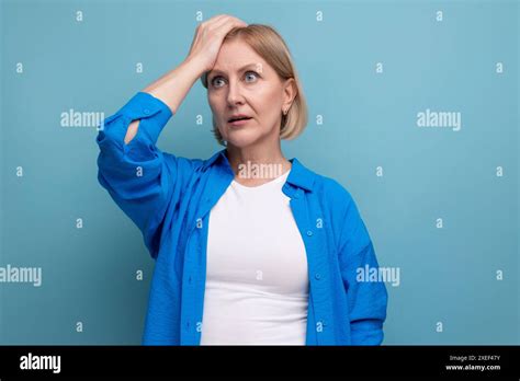 Surprised Blond Mature Woman In Disbelief On Blue Background With