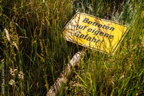 Schild Betreten auf eigene Gefahr liegt im hohen Gras ภาพถายสตอก