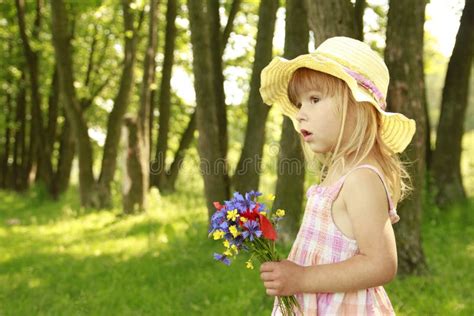 Belle Petite Fille Avec Un Bouquet Des Fleurs En Nature Image Stock